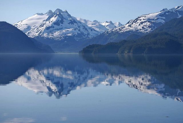 A placid view in Tutka Bay with near mirror-like conditions reflecting grand mountain scenery off the waters. Picture