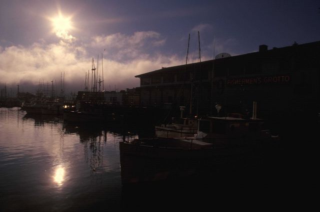 The Monterey waterfront silhouetted in the late afternoon with fog billowing in off the sea. Picture