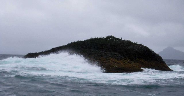 Surf washing an outlying rock along the Alaska coastline. Picture