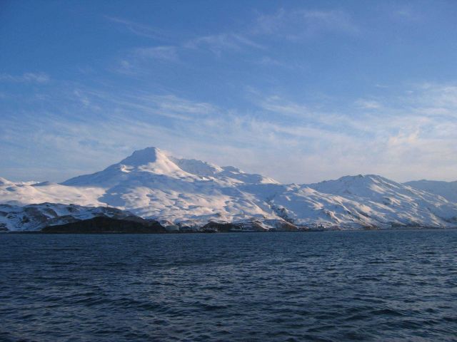 Snow covered mountains running down to the sea at Kodiak. Picture