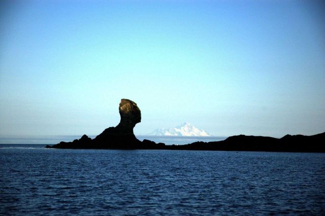 Illiamna Volcano seen to the right of a mushroom rock across Cook Inlet from Kachemak Bay. Picture