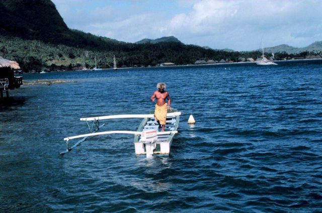 Combining the old with the new - a native with an outrigger canoe with an outboard motor. Picture