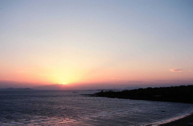 Coastal China with sun setting (maybe rising) behind a mountain. Picture
