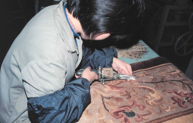 Chinese craftsman working on a rug. Picture