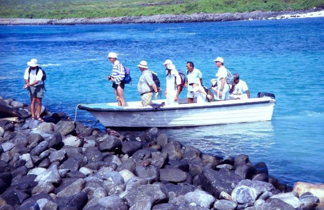 Eco-tourists with carmera s and packs debarking from skiff from cruise ship on boulder breakwater. Picture