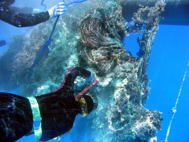 Cutting out heavy reef substrate material from derelict net prior to lifting onto inflatable boat for transport to CASITAS. Picture