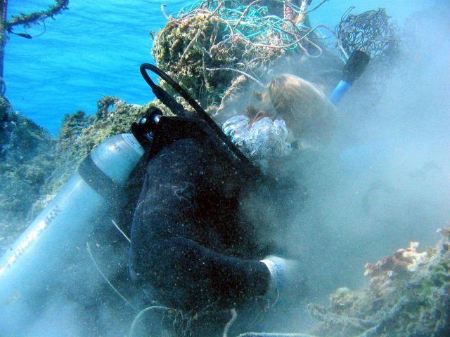 Scuba diver cutting derelict net material free prior to floating free portion to surface Picture