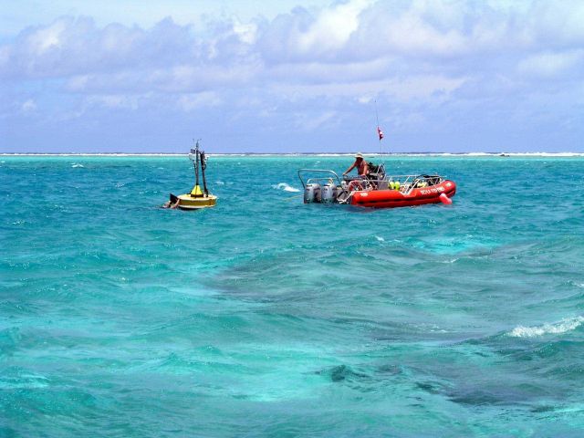 Oceanographers deploy a CREWS buoy inside an atoll. Picture