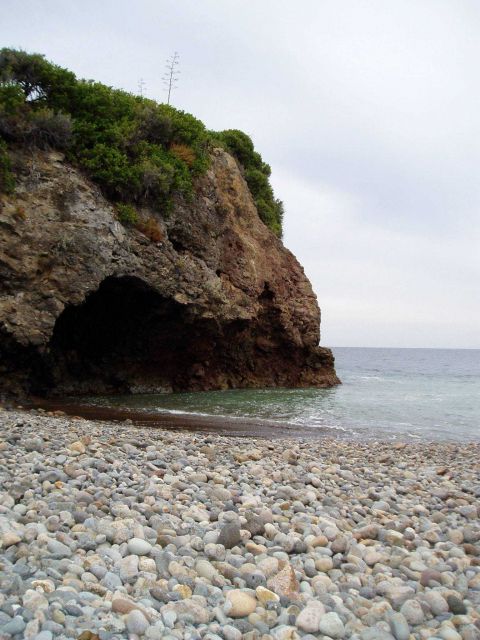 Beginnings of a sea cave or possibly an arch with a boulder beach in the foreground. Picture