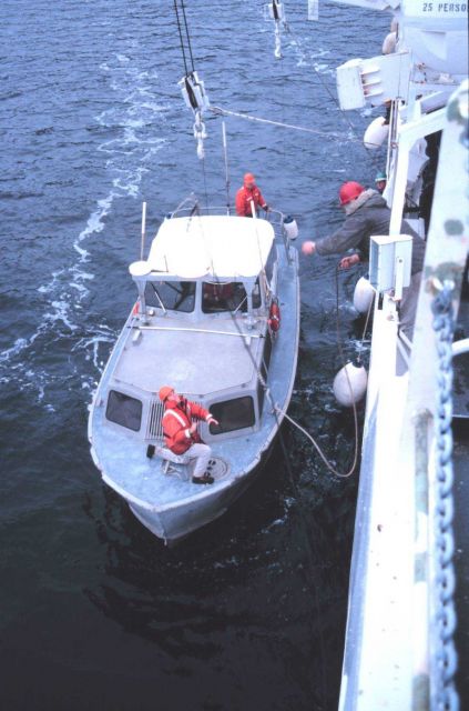 Seaman Surveyor Geno Gallinati tosses a leader-line to Senior Survey Tech Paul McAnally in preparation for hoisting RA-1 boat. Picture