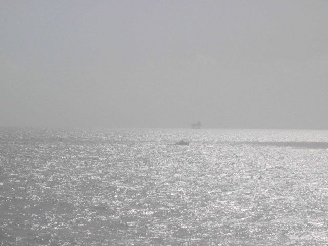 Survey launch and oil platform on a hazy day. Picture