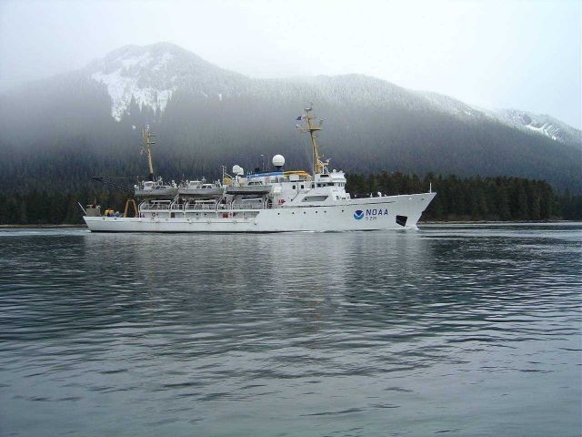 NOAA Ship RAINIER underway in Alaskan waters with snow-dusted mountains as backdrop. Picture