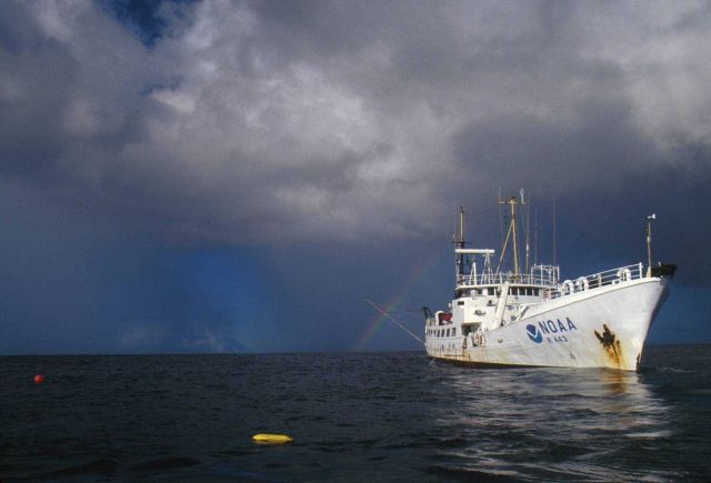 NOAA Ship TOWNSEND CROMWELL is rimmed by a rainbow while it stands by during a deep diving operation with down line and diver's PAM nearby. Picture
