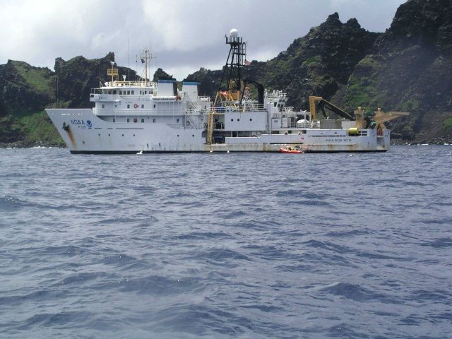 NOAA Ship OSCAR ELTON SETTE at anchor off a volcanic island. Picture