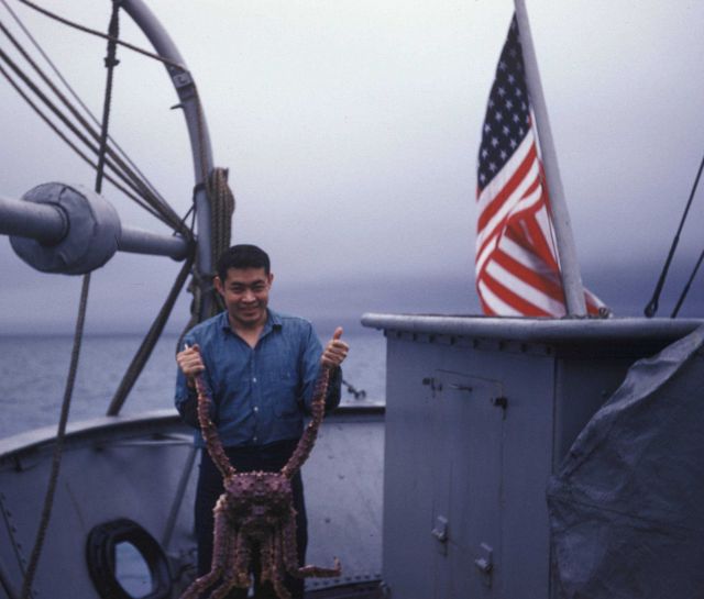 Member of steward's department on USC&GS Ship PATHFINDER displaying king crab that probably became part of dinner. Picture