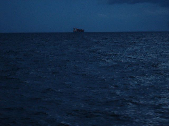 Twinkling lights of containership passing on a moonlit ocean. Picture