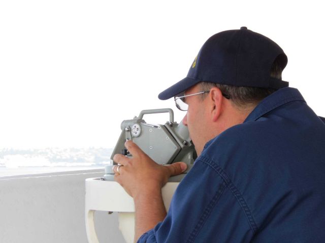 Taking a bearing with a bridge wing alidade. Picture