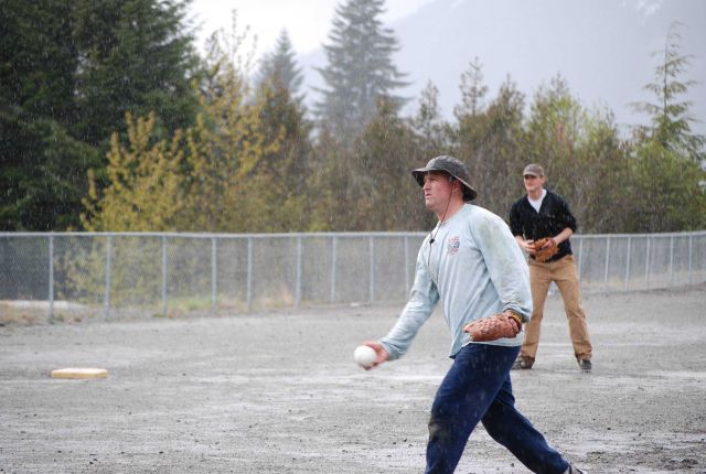 Captain Doug Baird of the NOAA Ship FAIRWEATHER displaying his best form while delivering a pitch in the midst of a drizzling rain. Picture