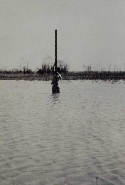 Determining sea level - just kidding! Rodman at bench mark covered by floodwaters Picture