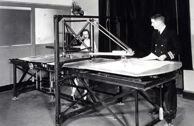 Officer discussing work with woman operating photogrammetric stereoplotter. Picture