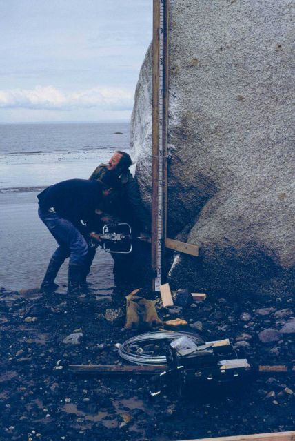 Chief Survey Technician Earl Krick supporting 2X4 while hole being drilled to place mountings to support tide staff. Picture