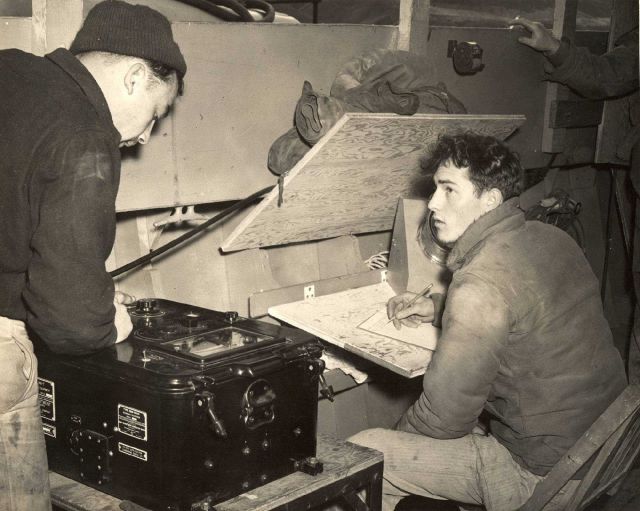 Reading depths off fathometer on the left and recording depths in field record book on right. Picture
