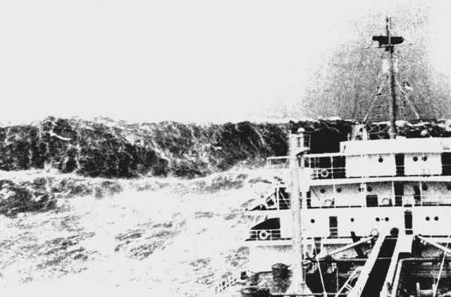 Merchant ship laboring in heavy seas as huge wave looms astern Picture