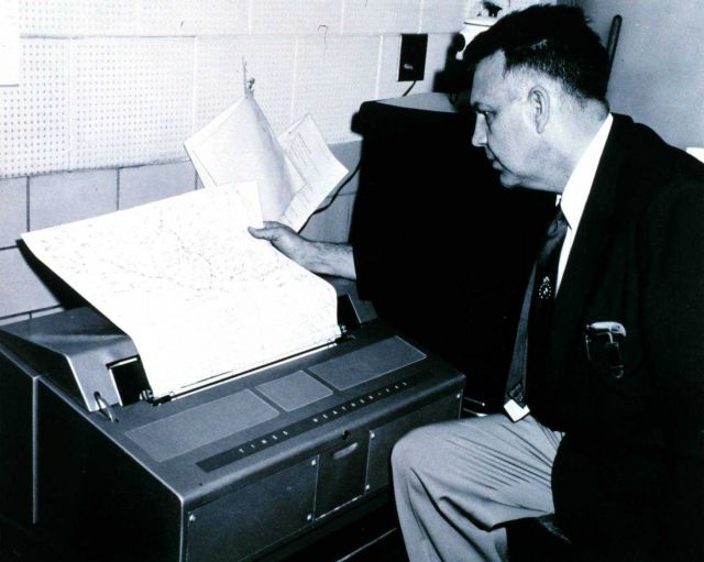 Weather Bureau meteorologist reading a weather map hot off the facscimile machine. Picture