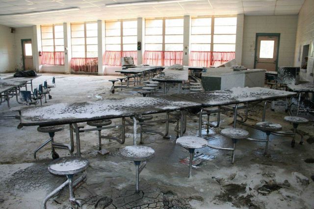 The inside of a school cafeteria with mud left on tables and stools after water receded. Picture