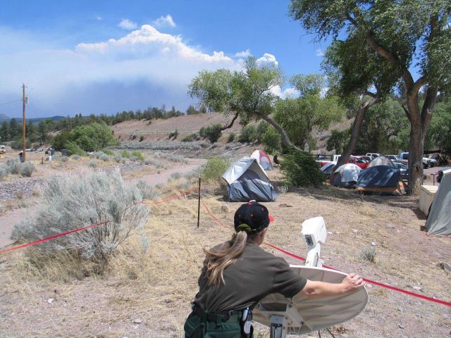National Weather Service IMET trainee Valerie Myers positioning the Direcway satellite dish while smoke from the Bear Fire is seen in the distance. Picture
