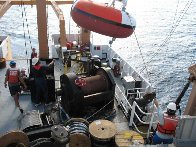 While the clouds approach and the TAO buoy streams aft with attached line, the deck crew of the NOAA Ship GORDON GUNTER move a second TAO to its pre-m Picture