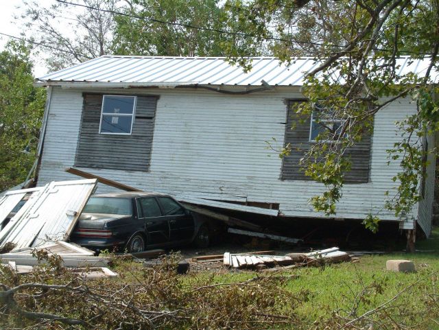 A house either floated off its foundation or was blown off its foundation and landed on this vehicle Picture