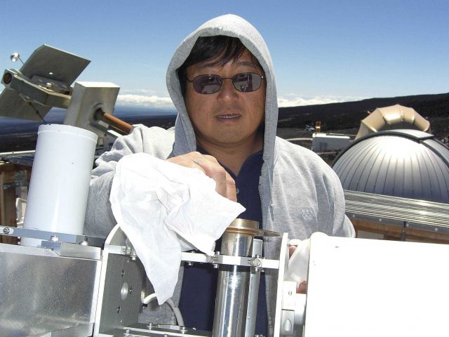 Paul Fukumura-Sawada cleans a sunlight monitoring instrument at NOAA's Mauna Loa Observatory. Picture