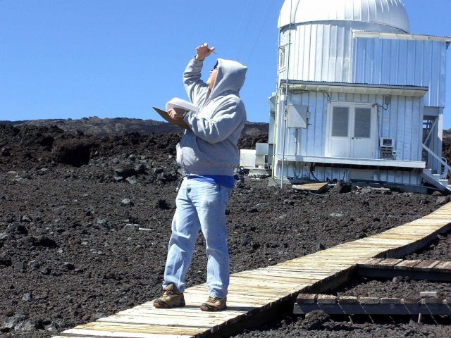 Paul Fukumura-Sawada glances at the sky near the sun to check for the presence of aerosols in the sky over NOAA's Mauna Loa Observatory. Picture