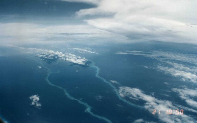 Reef seen surrounding elongate atoll with cloud streets above Picture