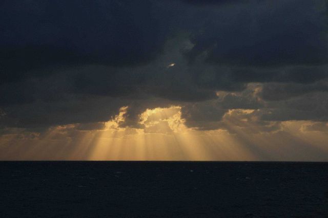 Glorious crepuscular rays terminating on the ocean surface. Picture
