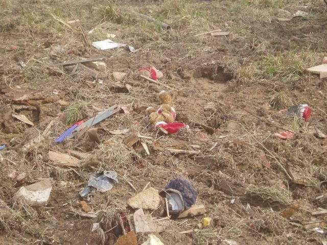 A poignant image of a child's stuffed animals strewn in a field by a tornado. Picture