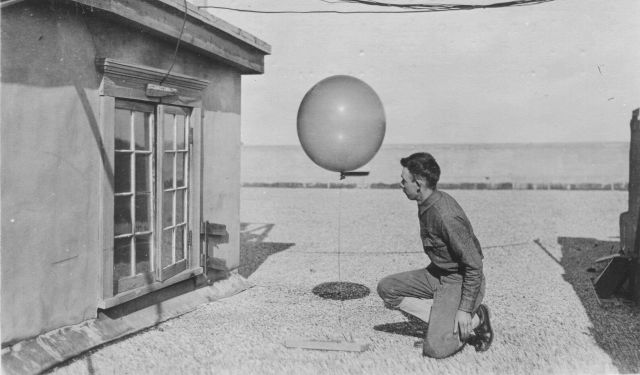 Signal Corps meteorological student Hall checking weather balloon weight prior to launching. Picture