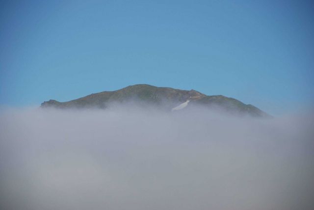 An Aleutian Island peaks its peak over the fog. Picture