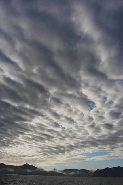 Clouds over the Alaska Peninsula as fog fills the valleys below as seen from offshore. Picture