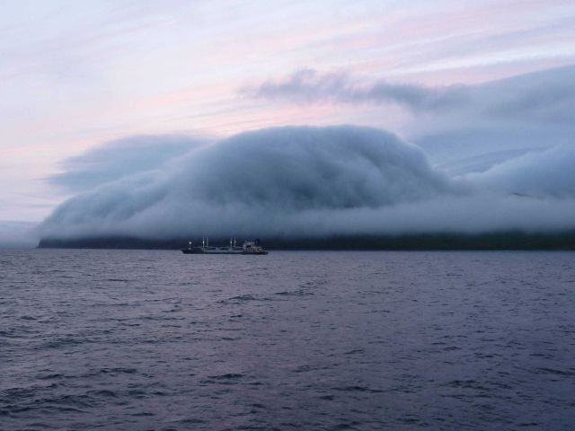 A gentle fog following topography at Dutch Harbor as a freighter leaves for an unknown port. Picture