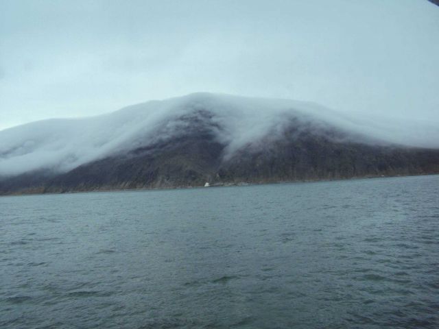 Fog draping a mountain and streaming down small valleys. Picture