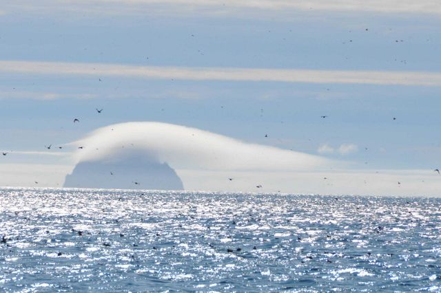 Orographic uplift forming fog over island with wind blowing from left to right. Picture