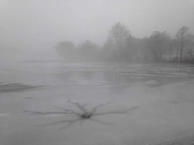 Radial pattern emanating from hole in ice over pond. Picture