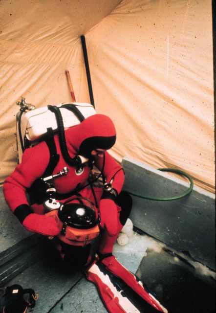Diver with rebreather and heated dry suit prepares to descend into the ice. Picture