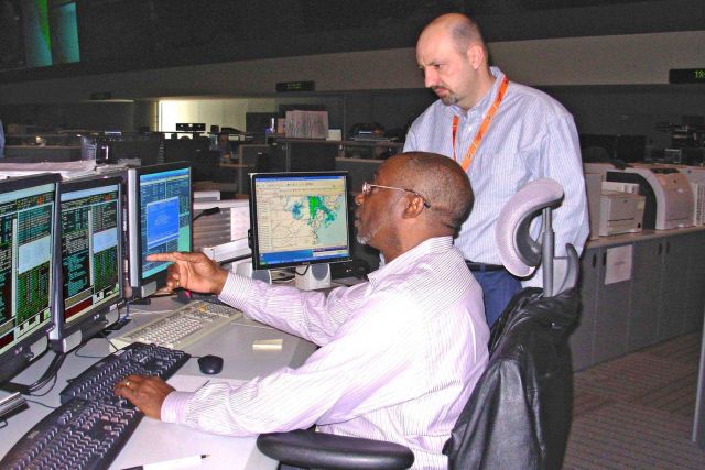 NOAA NESDIS employees Al Williams (seated) and Tom Boyd monitoring GOES-11 spacecraft from the NESDIS Satellite Operations Center. Picture