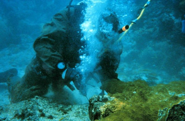 One diver prepares to attach coral, another diver works using surface supplied air. Picture