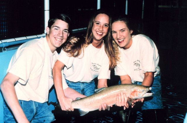Three students pose with a steelhead trout at their fish hatchery Picture