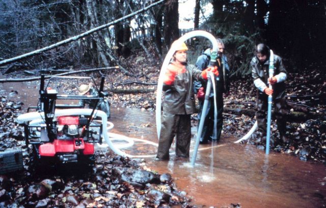Three workers use the pump used to loosen sand and gravel at Duck Creek. Picture