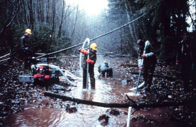 Three men in the river operate the pump. Picture